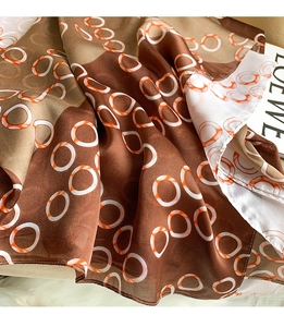 Detailed view of silk texture scarf featuring geometric circles and brown color blocking