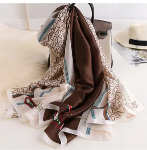 Close-up of elegant silk scarf with equestrian chain print draped on a leather handbag