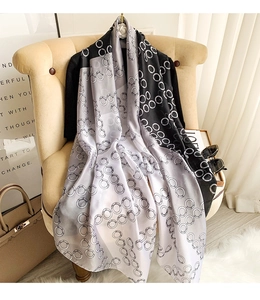 Detail of faux silk scarf with black and white circle print on a beige sofa