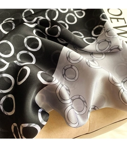 Detail of silk-like scarf with black and white ring patterns draped over a fashion magazine