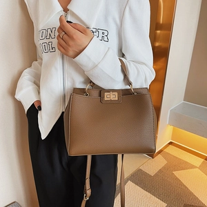 Brown lychee leather handbag with gold metal twist lock shown in a stylish fashion lifestyle