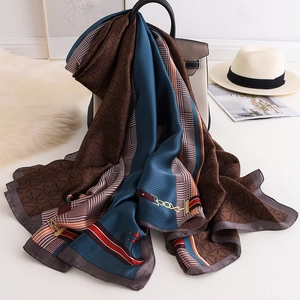 Elegant chain pattern silk scarf draped over a grey handbag with classic horsebit motifs