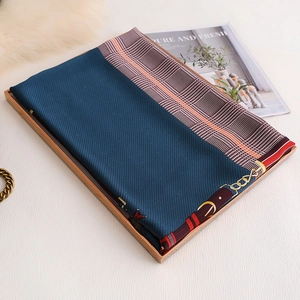 Detailed view of silk-like scarf with equestrian chain prints folded on golden tray