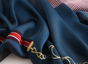Detail of silk-like scarf featuring vintage chain patterns and soft lake blue texture