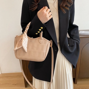 Beige bucket bag with silk scarf handle, worn by model in a minimalist stylish setting