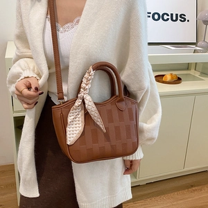 Brown leather bucket bag with square texture and patterned silk scarf on handle