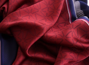 Macro shot of silk satin fabric showing elegant red geometric star patterns and texture