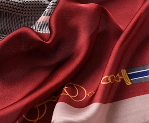 Macro detail of silky dark red scarf showing houndstooth patterns and gold chain prints