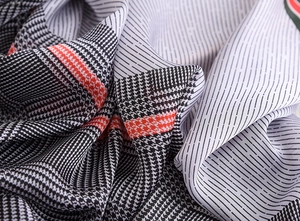 Macro shot of faux silk scarf with black houndstooth pattern and orange stripe accents