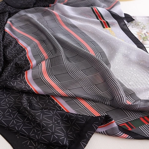 Detail of luxury silk scarf showing intricate chain patterns and soft fabric texture