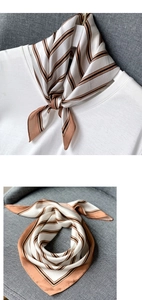 Détail d'un foulard en soie à rayures marron et noires sur un t-shirt blanc et du tissu