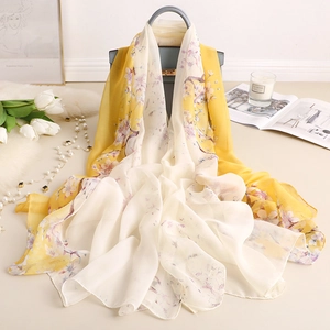 Floral print long beach scarf shawl in yellow gradient draped over a blue handbag