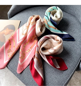 Détail de foulards en soie avec motifs de chaînes équestres sur une chaise en tissu