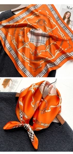 Détail du foulard en soie orange avec bordure à carreaux et motifs de mors et chaînes