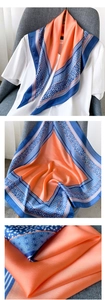 Détails d'un foulard en soie orange avec bordures géométriques bleues et pois élégants
