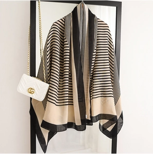 Détail d'un châle léger à rayures beige drapé sur un cadre noir avec texture fine