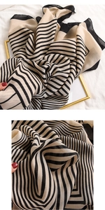 Détail macro d'un châle à rayures respirant avec bordure noire fine au toucher lin