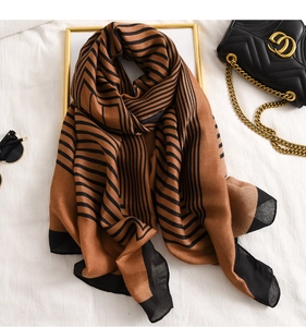 Détail d'une écharpe rayée douce avec motifs géométriques marron et noir sur le tissu