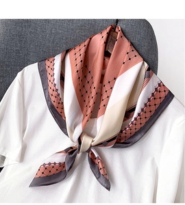 Détail d'une écharpe en satin soyeux avec des motifs hexagonaux roses et gris