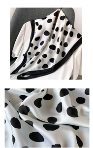 Détail du foulard en satin blanc à pois noirs montrant la texture luxueuse du tissu