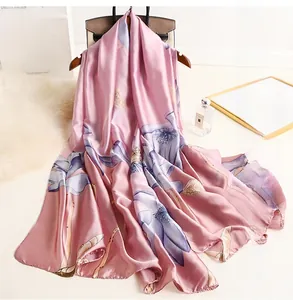 Detail of pink silk scarf with blue lotus patterns hanging on a wooden hanger