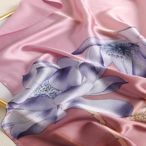 Detail of soft pink silk scarf featuring elegant purple lotus floral print and satin texture