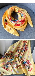 Détail de l'écharpe jaune soyeuse avec motifs floraux et texture satinée lisse