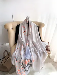 Detail view of long silk-feel scarf with pink floral ink patterns on a beige chair