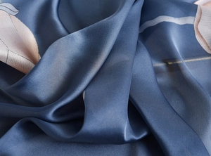 Macro shot of midnight blue silk scarf featuring elegant pink floral patterns and soft folds