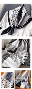 Vue détaillée d'un foulard en soie géométrique à pois et rayures sur un t-shirt blanc