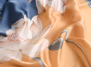 Detailed view of silk scarf fabric showing elegant lotus print and smooth glossy texture