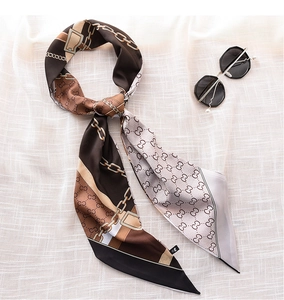 Detail of narrow silk scarf with chain print and lettering on textured background