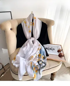 Close-up of silk-like scarf with yellow plum blossom patterns draped on an armchair