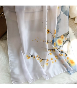 Detailed texture of white silk scarf with yellow flower branches on plush carpet