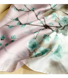 Detailed view of pink silk scarf with blue ginkgo leaf patterns and smooth texture
