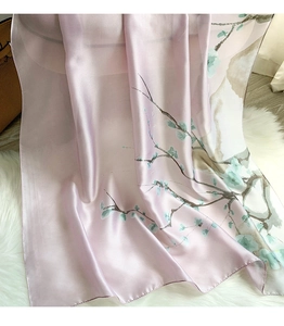 Detail of silk-like scarf with ginkgo leaf pattern and fine hemmed edges on white fur