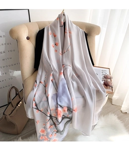 Close-up of silk scarf with floral gingko pattern draped on a beige armchair