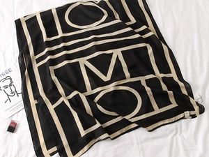 Flat lay of large cotton scarf with gold geometric patterns on a soft white background