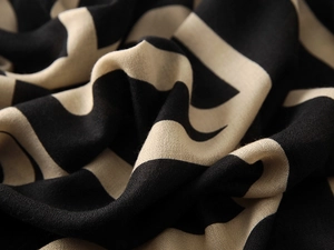 Close-up detail of soft woven cotton-linen fabric with geometric patterns in black and beige