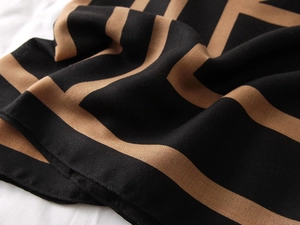 Detailed close-up of high-quality cotton linen scarf with black and camel geometric pattern