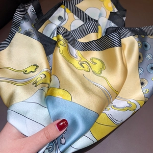 Detail of silk-like scarf featuring yellow and blue patterns with elegant satin luster