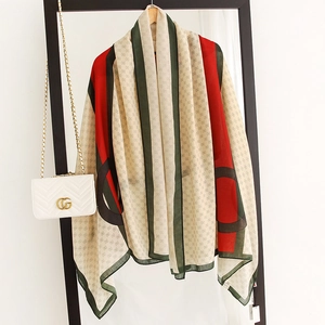 Close-up of lightweight linen-touch shawl with red-green stripes and monogram pattern