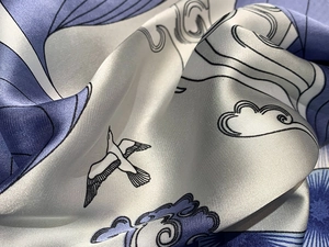 Detail of silk scarf showing elegant cranes and cloud patterns on satin fabric