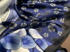 Macro shot of navy blue silk scarf featuring intricate floral prints and satin texture