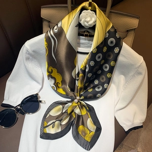 Floral print silk scarf with pearl buckle on white knit top and leather bag background