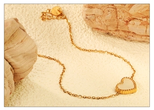Détail du pendentif cœur doré avec nacre blanche et bordure perlée élégante