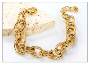 Dettaglio del bracciale a catena dorata con maglie intrecciate e chiusura a moschettone
