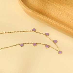 18K gold plated necklace with purple enamel heart pendants on a beige background