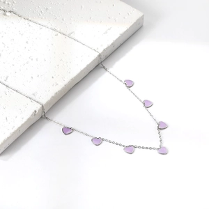 Macro detail of seven small purple enamel heart pendants on a silver stainless steel chain