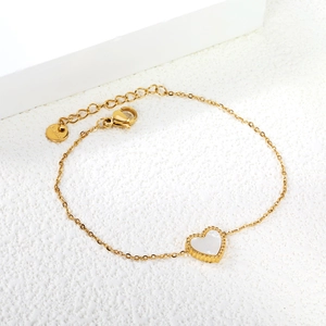Bracelet doré avec pendentif cœur nacré blanc et bordure perlée sur fond blanc